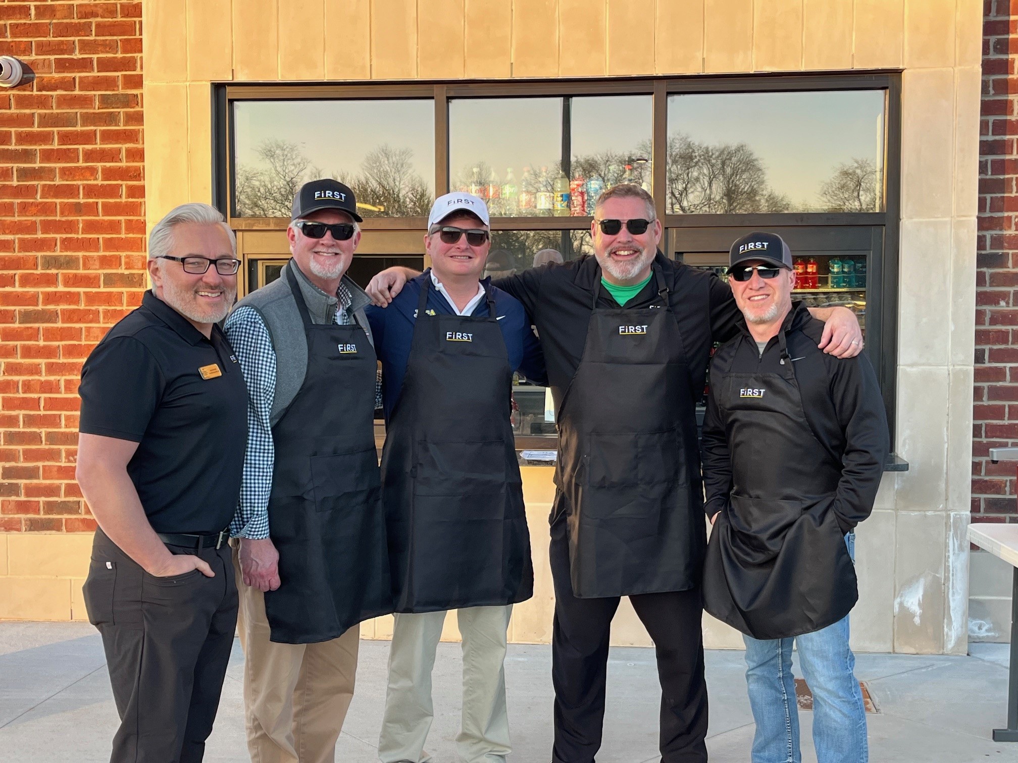 Five men standing together outside wearing First National Bank Middle Tennesse aprons.